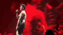 a shirtless man is singing into a microphone on stage