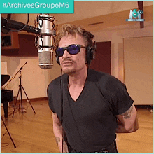 a man wearing sunglasses and headphones stands in front of a microphone with archivesgroupem6 written on the bottom