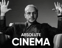 a man sitting in a chair with his hands in the air with the words absolute cinema below him