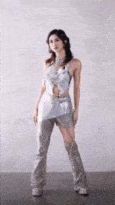 a woman in a silver outfit is standing in front of a wall .