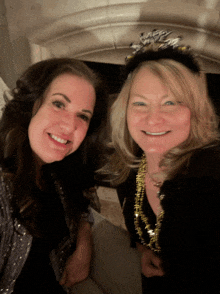 a woman wearing a new year 's eve headband smiles next to another woman