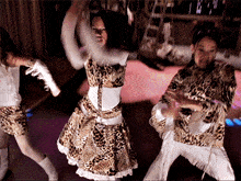 a woman in a leopard print dress is dancing with two other girls
