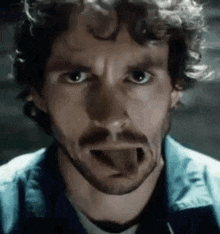 a man with a beard is sticking his tongue out in a close up of his face .
