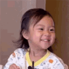 a little girl is smiling while wearing a microphone around her neck .