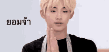 a young man with blonde hair and a black shirt is clapping his hands .