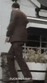 a man in a suit is walking down a sidewalk and holding a gun .