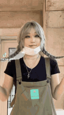 a woman wearing overalls and a mask is making a funny face