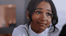 a woman in a white sweater is making a funny face and smiling .