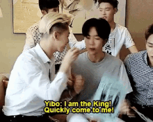 a group of young men are sitting around a table and one of them says " yibo i am the king quickly come to me