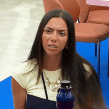 a woman with long hair is sitting next to a bottle of purple liquid