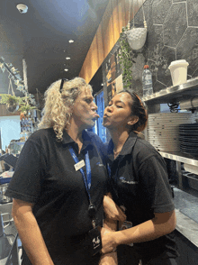 a woman wearing a lanyard with the letter m on it is kissing another woman