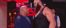 a bald man and a bearded man are standing next to each other .