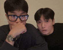 a man wearing glasses and a watch looks at the camera