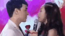 a man and a woman are kissing while the man is holding a microphone .