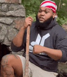 a man in a hurley sweatshirt holds a wooden stick