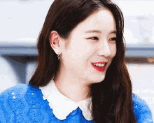 a close up of a woman wearing a blue sweater