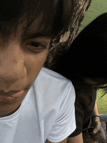 a close up of a person 's face with a woman holding a cell phone