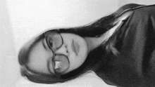 a black and white photo of a girl wearing glasses and a black shirt .