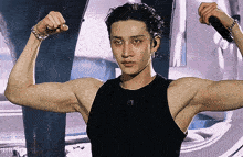 a man is flexing his muscles while holding a microphone and wearing a black tank top with the letter f1 on it