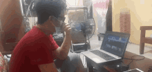 a man wearing a mask is sitting in front of a laptop computer