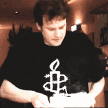 a man wearing a black shirt with a candle and a cross on it