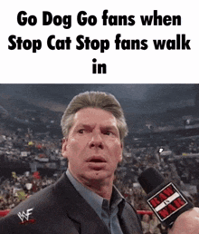 a man in a suit is talking into a microphone with the words go dog go fans when stop cat stop fans walk in