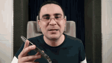 a man wearing glasses is holding a cell phone