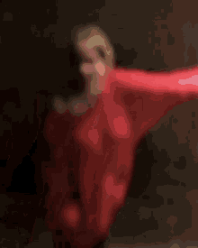 a woman in a red dress is dancing with her arms outstretched in the dark .