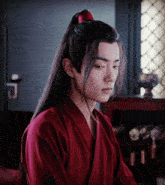 a young man with long hair wearing a red shirt