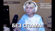 a man wearing headphones and a shirt that says " без спама " stands in front of a microphone