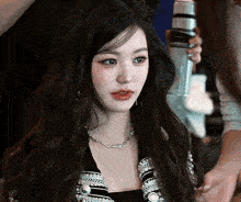 a woman with long black hair is holding a microphone in her hand .