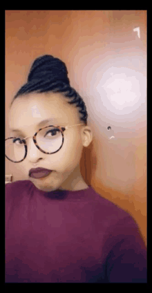 a woman wearing glasses and a purple shirt has the number 1 on her face