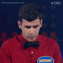 a man wearing a red shirt and a bow tie has an anthony sticker on his shirt