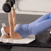 a woman is laying on a mat lifting a dumbbell that says 17.5 on it