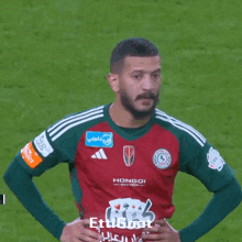 a man wearing a hongoi jersey stands on a soccer field