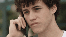 a man with curly hair talking on a cell phone