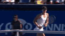 a woman is holding a tennis racquet in front of a banner that says tennis