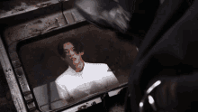 a man in a white uniform is looking out of a window