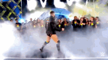 a man is walking on a stage in front of a crowd of people .