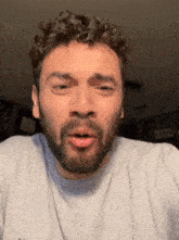 a man with a beard and curly hair is wearing a white shirt