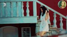 a woman in a white dress walks down stairs