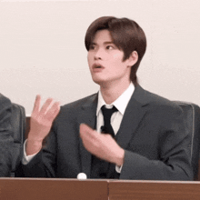 a man in a suit and tie is sitting in a courtroom .