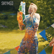 a man is covered in paint while holding a water gun and the word skymed is on the bottom