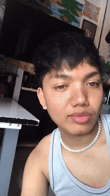 a man wearing a pearl necklace and a tank top
