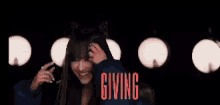 a woman wearing cat ears is smiling and holding her hair in front of a group of lights .