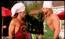two men wearing chef hats are standing next to each other and one is wearing an apron that says bravo on it