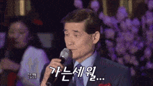 a man in a suit is singing into a microphone with korean writing on it .