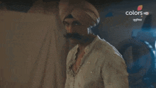a man in a turban is standing in front of a door with the words colors hd written on it