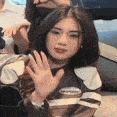 a woman in a leather jacket is sitting on a couch waving at the camera .