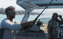 a man holding a fishing rod on a boat while another man looks through binoculars
